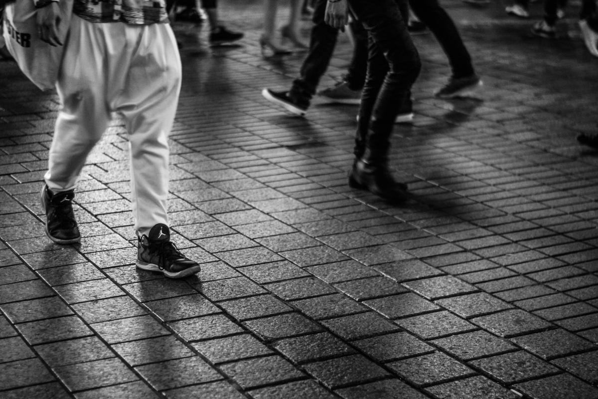 black and white photo of people walking but it is only their feet and legs