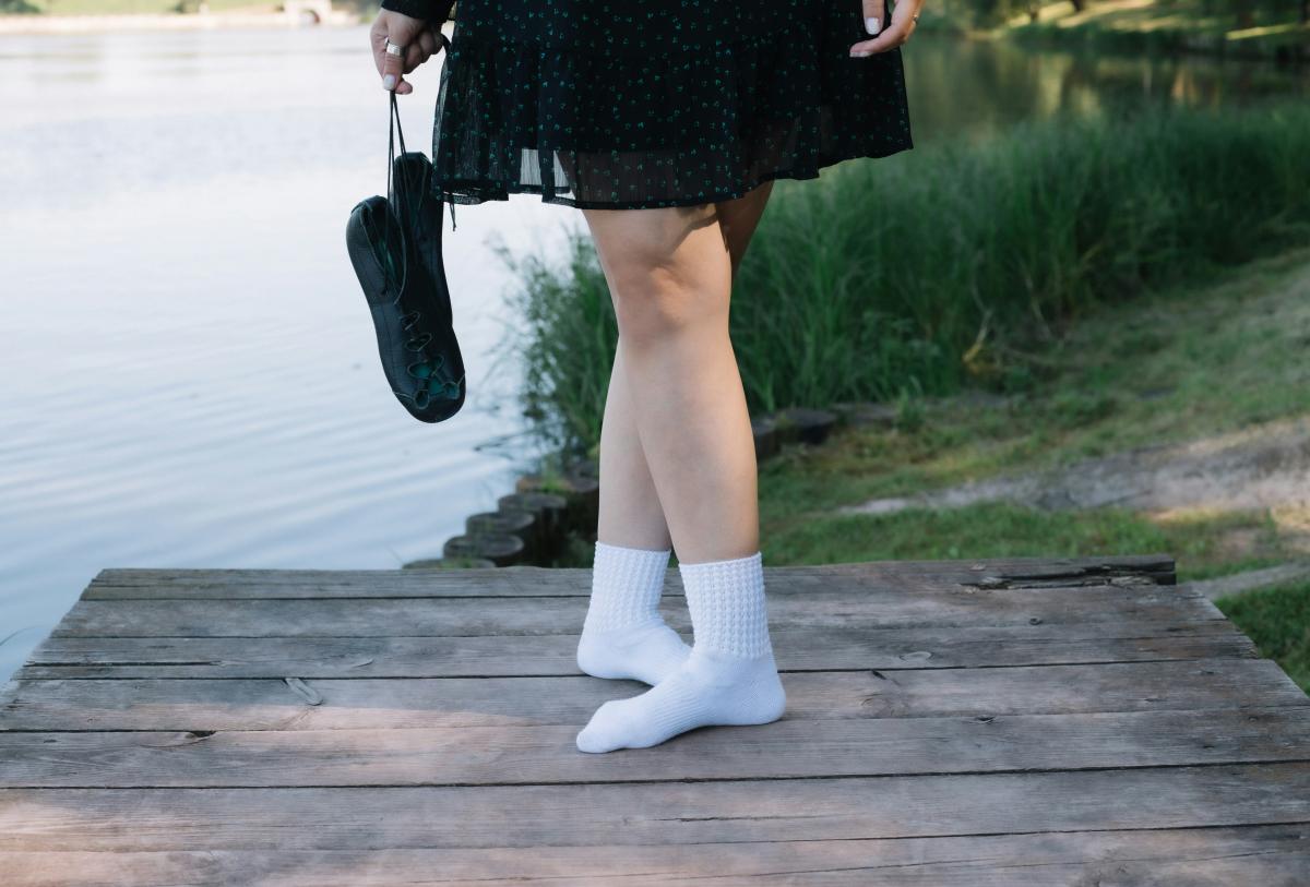 feet of woman in dance ready position with traditional Irish dance shows dangling from hand