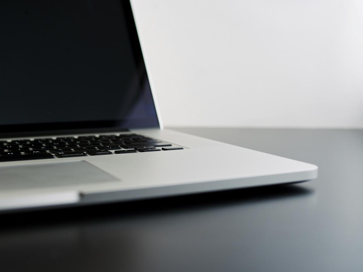 silver laptop computer sitting open on black desk