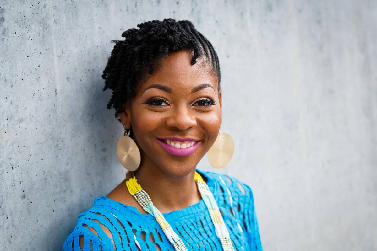 Kamica King, a black woman with short hair, smiles at the camera. She wears a blue shirt