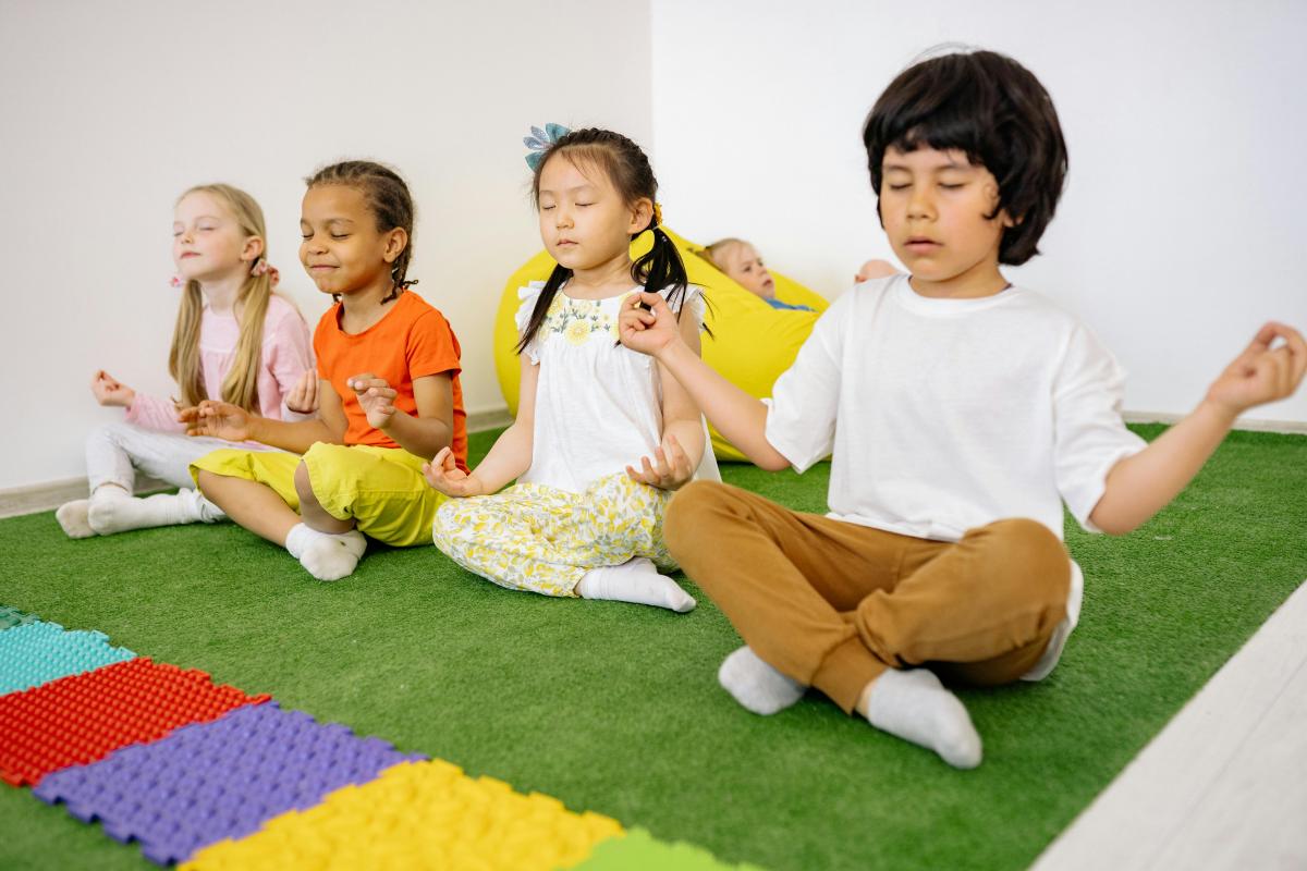 four children doing a crossed legs yoga pose
