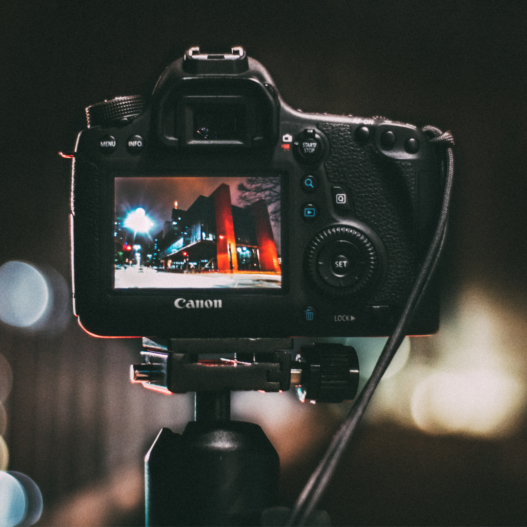 A Canon camera with a brightly lit nighttime building on the dslr screen