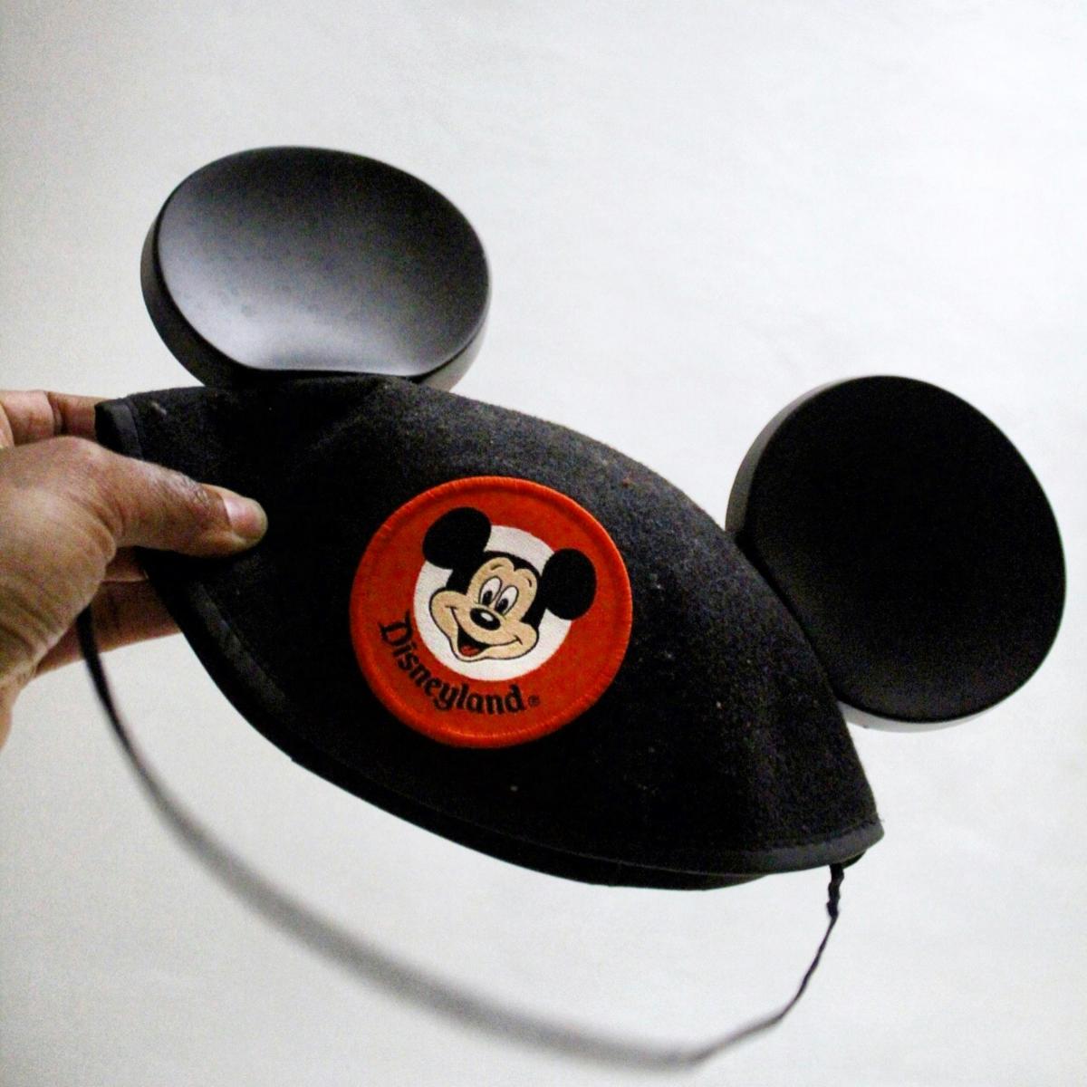person holding a black mouse ears hat with Mickey Mouse embroidered on the front