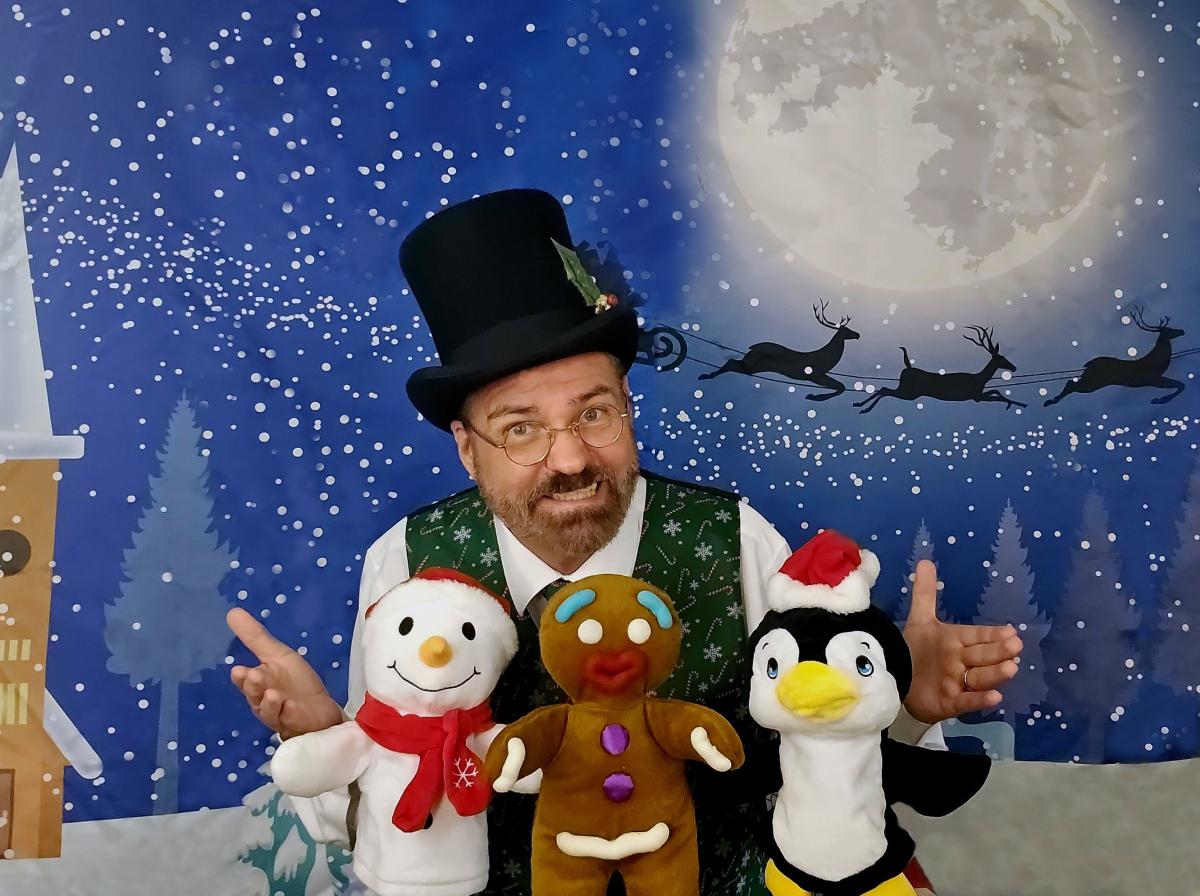 Brett Roberts holding holiday puppets with a winter background