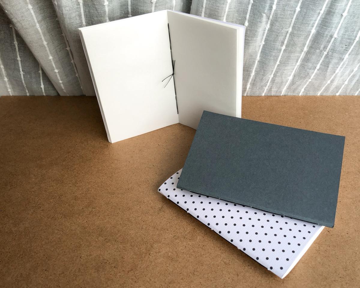 Three homemade notebooks with different covers sit on a table.