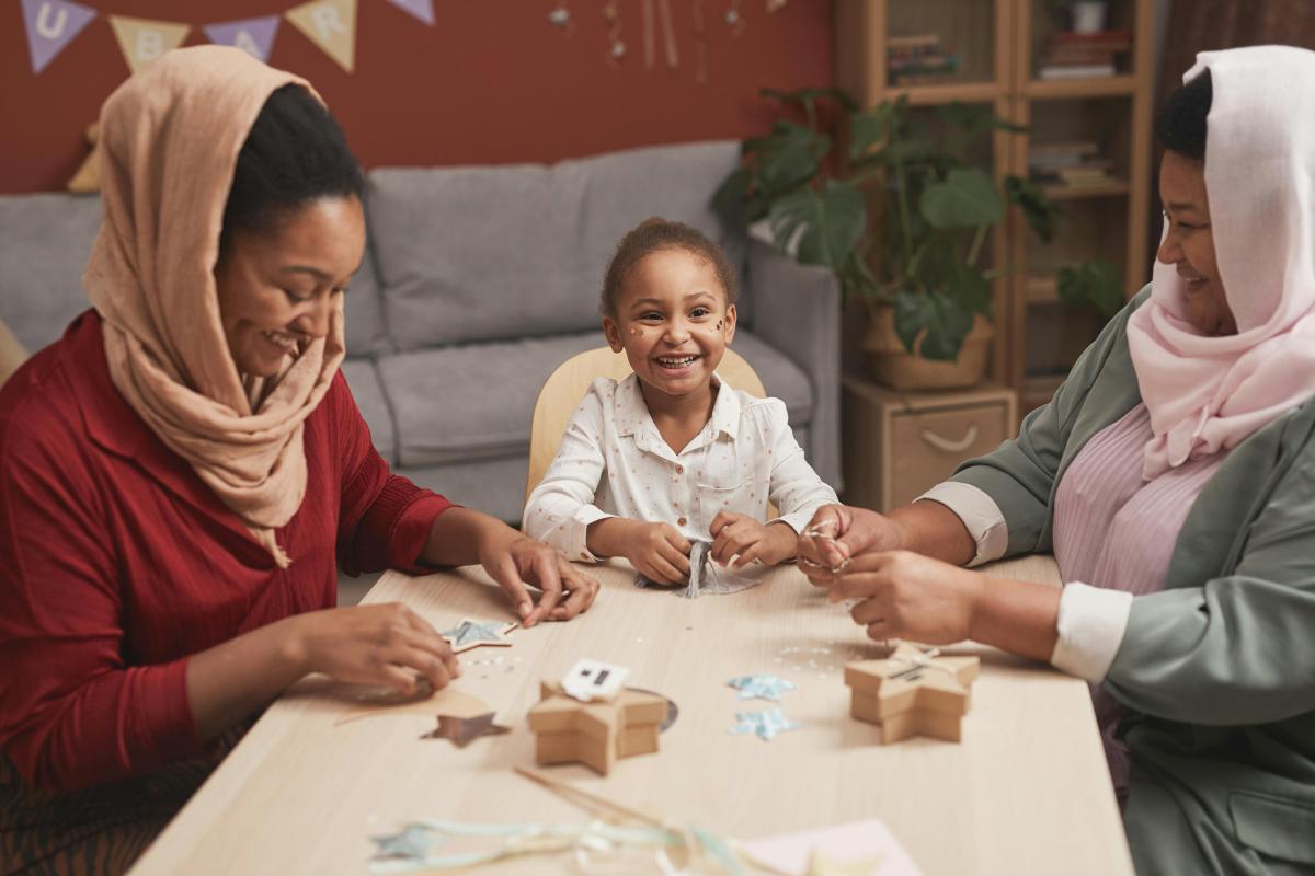 Two adults and a child sit at a table doing a craft.