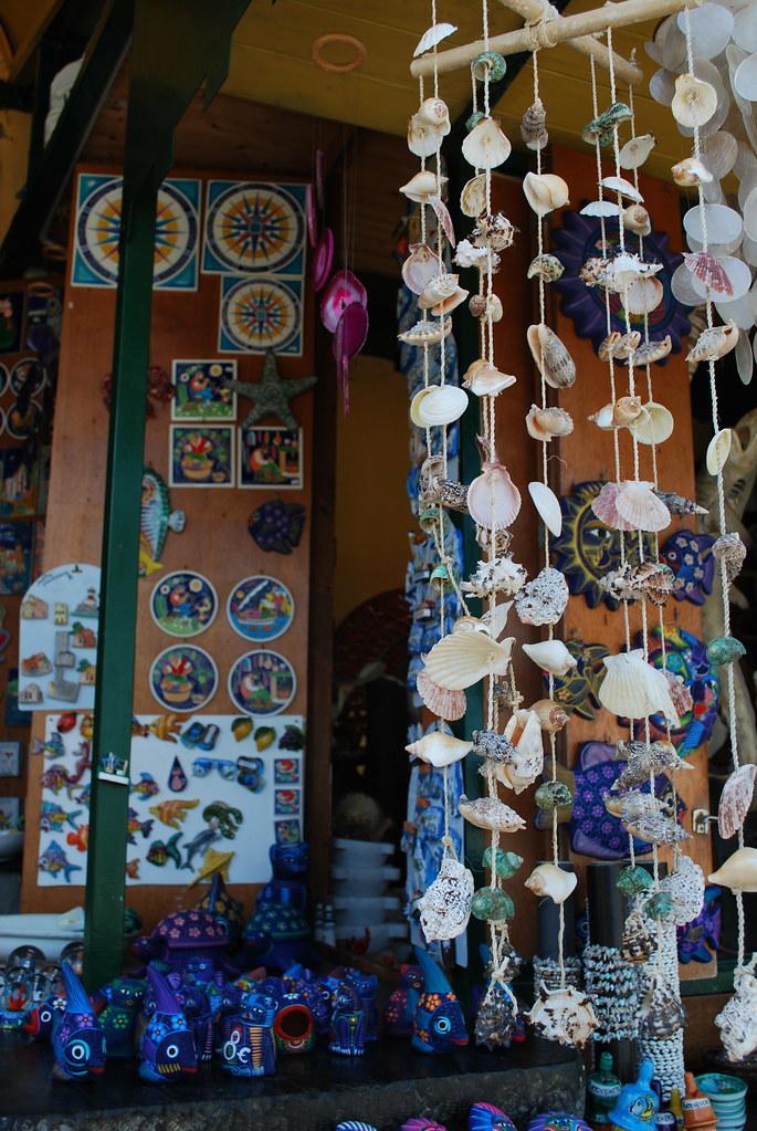 A wind chime made of wood and seashells hangs from a ceiling.