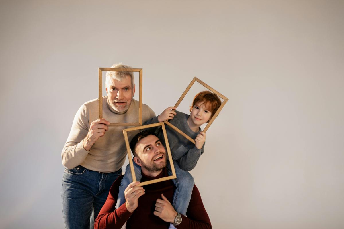 A family poses together with their faces in picture frames.