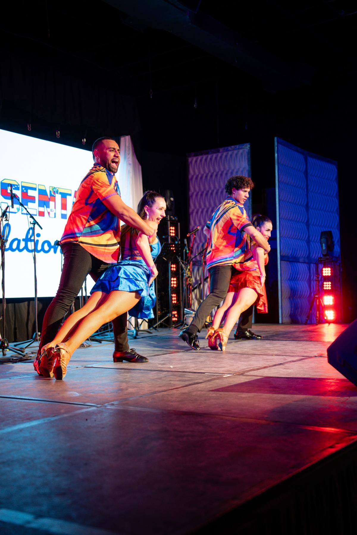 two couples dancing in the salsa caleña style on a raised stage