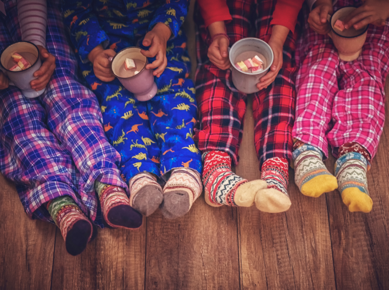 Four pair of children's legs in cozy pajamas and fuzzy socks 